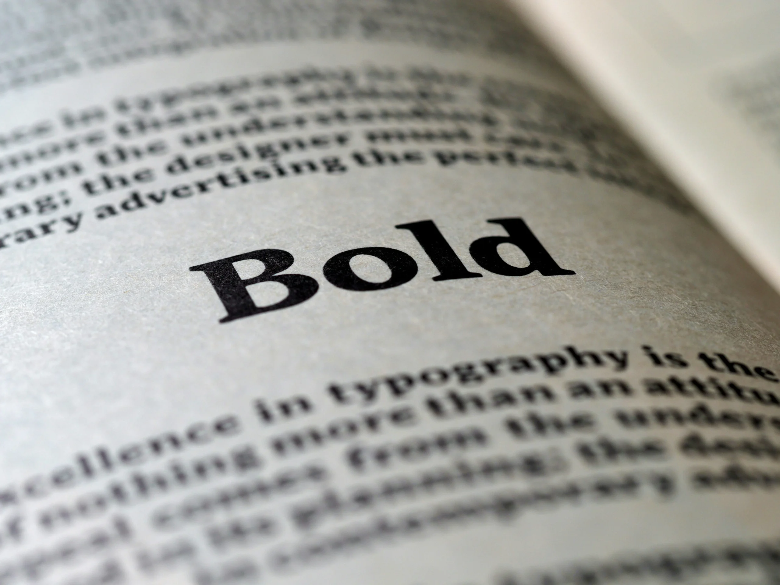 The words "bold" in bold on the pages of a book to draw emphasis on the word.